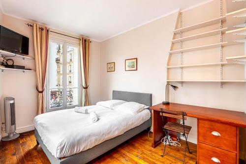 une chambre avec un lit, un bureau et une fenêtre dans l'établissement GuestReady - Charmant Appartement Lumineux, à Paris