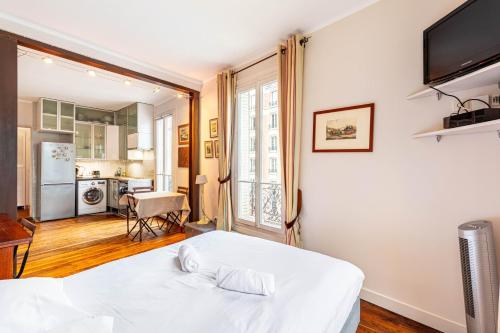 Cet appartement comprend une chambre avec un lit blanc et une cuisine. dans l'établissement GuestReady - Charmant Appartement Lumineux, à Paris