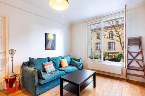 un salon avec un canapé bleu et une table dans l'établissement GuestReady - Appartement Chic et Élégant, à Paris