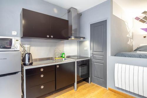 une petite cuisine avec un évier et un lit dans l'établissement GuestReady - Studio design et fonctionnel, à Paris