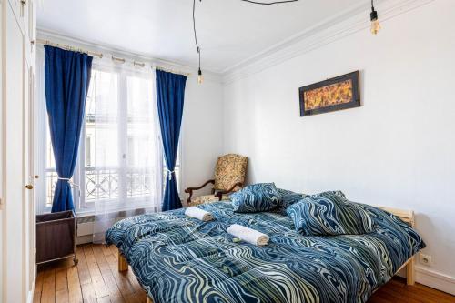 une chambre avec un lit avec une couette bleue dans l'établissement GuestReady - Espace Cosy au Cœur de la Ville, à Paris