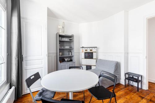 une salle à manger blanche avec une table et des chaises blanches dans l'établissement GuestReady - Séjour Confortable près de Montmartre, à Paris