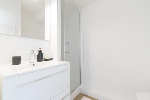 une salle de bain blanche avec un lavabo et un miroir dans l'établissement La Goélette à Préfailles - Studio 2 Personnes vue mer, parking, à Préfailles