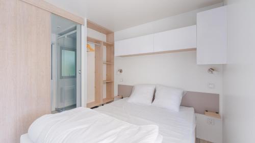 une chambre avec un lit blanc et un miroir dans l'établissement Camping Etennemare, à Saint-Valery-en-Caux