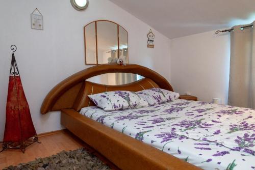uma cama com uma cabeceira em madeira num quarto em Vila Apartmani Astoria em Podgorica