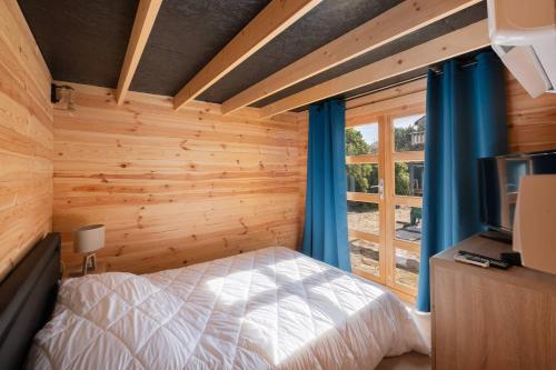 - une chambre avec des murs en bois et un lit avec des rideaux bleus dans l'établissement AS24411 - Studio cabine + chalet avec jardin et parking, au Grau-du-Roi