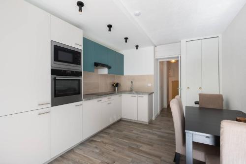 une cuisine avec des placards blancs et une table noire dans l'établissement AS24411 - Studio cabine + chalet avec jardin et parking, au Grau-du-Roi