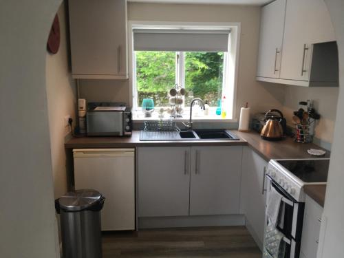 a kitchen with white cabinets and a sink and a window at Ruthven House Holiday Cottages in Kingussie