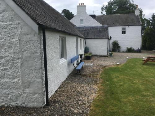 a white house with a blue bench in front of it at Ruthven House Holiday Cottages in Kingussie