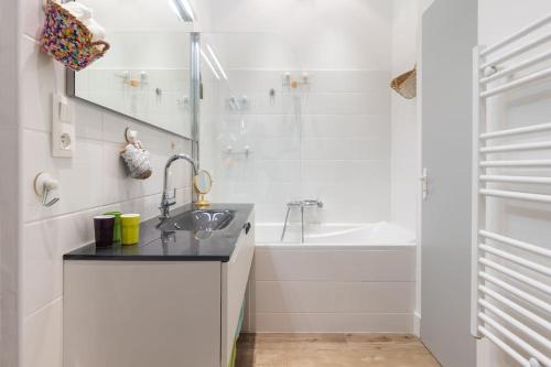 La salle de bains blanche est pourvue d'un lavabo et d'une baignoire. dans l'établissement L'Épicurien, Beau T2, Centre Historique, à Montpellier