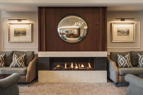 - une cheminée dans une pièce avec 2 canapés et un miroir dans l'établissement Lodore Falls Hotel & Spa, à Keswick