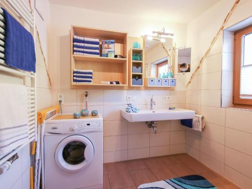 ein Badezimmer mit einer Waschmaschine und einem Waschbecken in der Unterkunft Cosy holiday flat in a farmhouse in Taxenbach