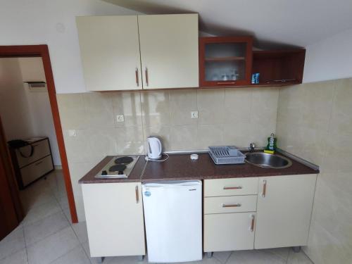 a small kitchen with white cabinets and a sink at Glory Suites in Budva