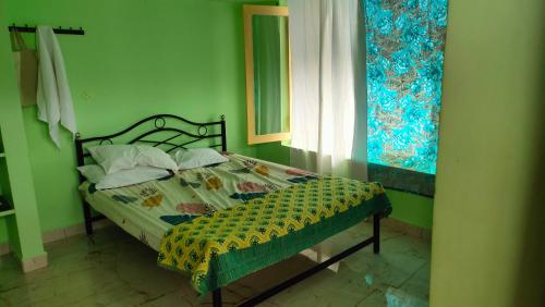a green bedroom with a bed with a comforter and pillows at Ram Guest House in Tiruvannāmalai