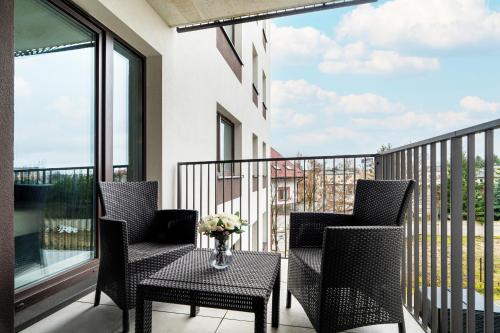 a balcony with two chairs and a table with a vase of flowers at Beautiful Apartment with Balcony & Free Garage by Renters in Poznań