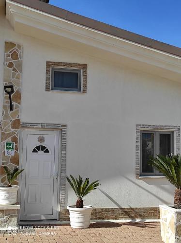 a white house with potted plants in front of a door at Re Sole Resort&Spa in Grottaglie