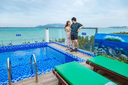 a man and a woman standing next to a swimming pool at Azura Gold Hotel & Apartment in Nha Trang