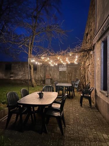 a patio with a table and chairs and lights at Aux 2 cerisiers in Virton
