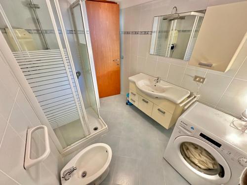 a bathroom with a toilet a sink and a washing machine at Casa Alba in Stintino