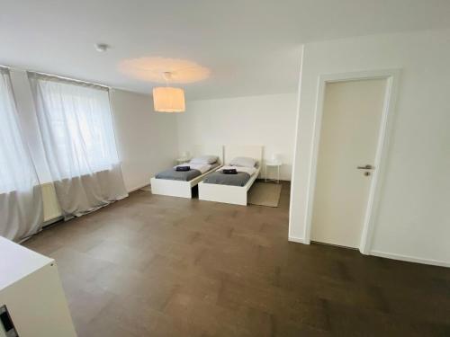 a white room with two beds and a door at Modernes, vollmöbliertes Apartment in ruhiger Lage in Hemer