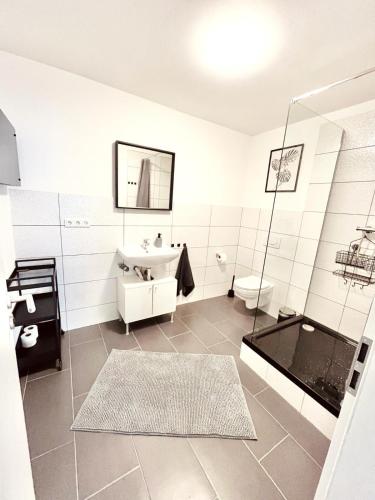 a white bathroom with a shower and a sink at Modernes, vollmöbliertes Apartment in ruhiger Lage in Hemer