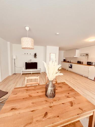 uma sala de estar com um vaso de flores numa mesa de madeira em Modernes, vollmöbliertes Apartment in ruhiger Lage em Hemer