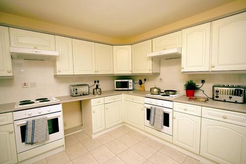 a white kitchen with white cabinets and appliances at 24/7 London Hostel in London