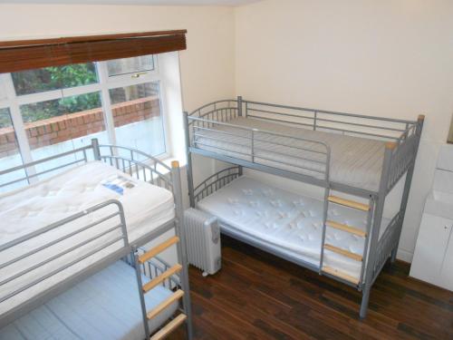 2 łóżka piętrowe w pokoju z oknem w obiekcie 24/7 London Hostel w Londynie