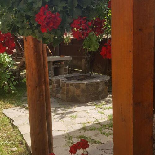 a wooden post with a bench and red flowers at Casa ,,Kiss-lak,, in Praid