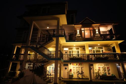 a three story building with a balcony at night at Hostelgia in Manāli