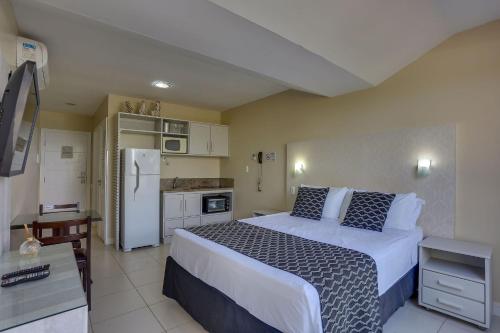 a bedroom with a large bed and a kitchen at Flat Pietra in Florianópolis