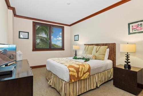 a bedroom with a bed with a desk and a tv at Ko Olina Beach Villas O402 in Kapolei