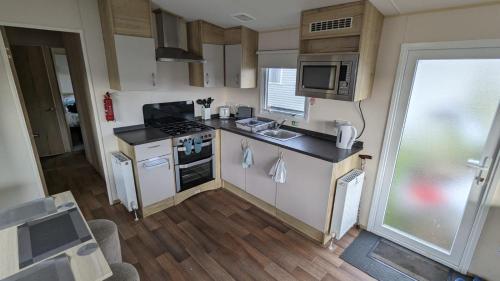 a small kitchen with a stove and a microwave at Superb 8 Berth Caravan At Steeple Bay Holiday Park, Essex Ref 36039f in Southminster