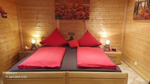 a bedroom with two red pillows on a bed at Pfalz-Apartment Mein Chalet in Großkarlbach