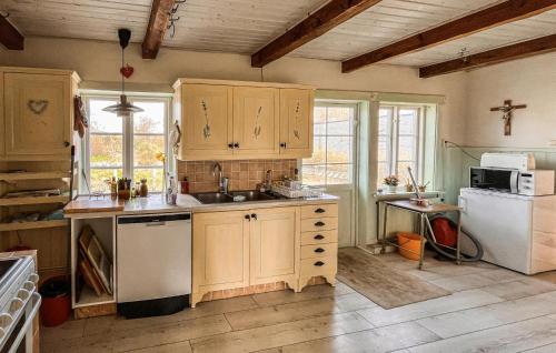 cocina con armarios de madera, fregadero y nevera en Amazing Home In Jonstorp With Kitchen, en Jonstorp