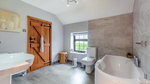 a bathroom with a tub and a toilet and a sink at Wye Cottage near Hassop in Eyam