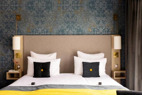 a bedroom with a large bed with black and white pillows at James Boutique Hôtel Colmar centre in Colmar