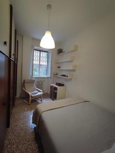 a bedroom with a bed and a chair and a window at Gavirate House MM Lotto in Milan