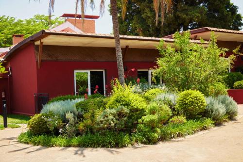 a red house with a garden in front of it at Relais des Plateaux & Spa– Ivato International Airport in Antananarivo