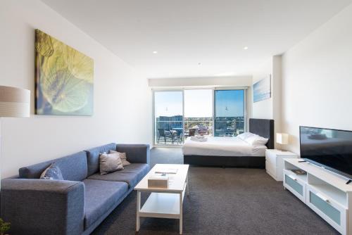 a living room with a couch and a bed at Vision Apartments On Morphett with Parking in Adelaide