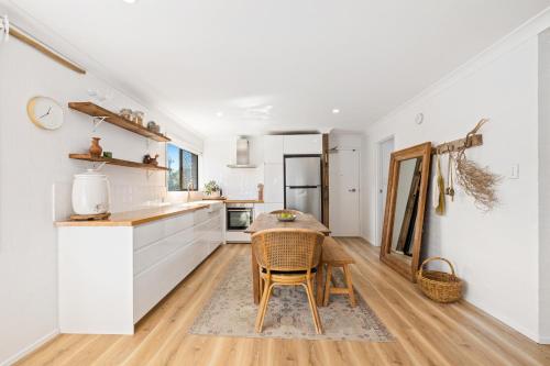 uma cozinha com armários brancos e uma mesa com uma cadeira em Boho Style 2BR apartment in Kingscliff by uHoliday em Kingscliff