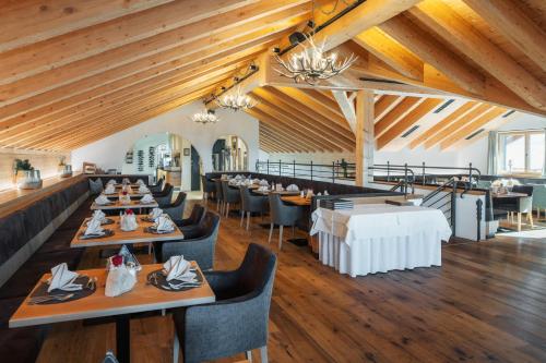 una sala da pranzo con tavoli, sedie e soffitti in legno di Bergresort Das Jochelius a Nauders