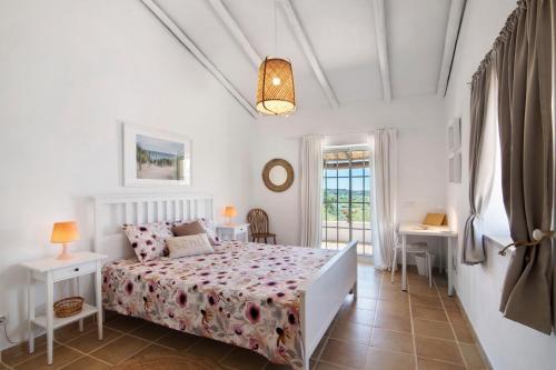 um quarto branco com uma cama e uma janela em Casa Noah em São Bartolomeu de Messines