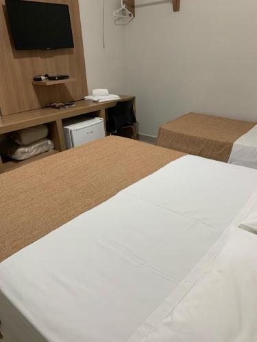 a hotel room with two beds and a television at Hotel Ouro Verde in Três Pontas