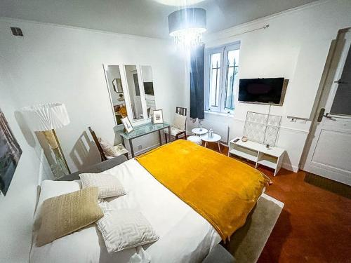 une chambre avec un grand lit avec une couverture jaune dans l'établissement Cocon Versaillais, à Versailles