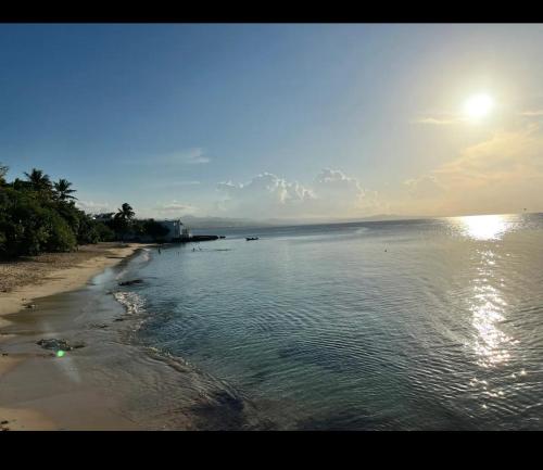 una spiaggia con il sole che splende sull'acqua di E & J Lifestyle a Río San Juan