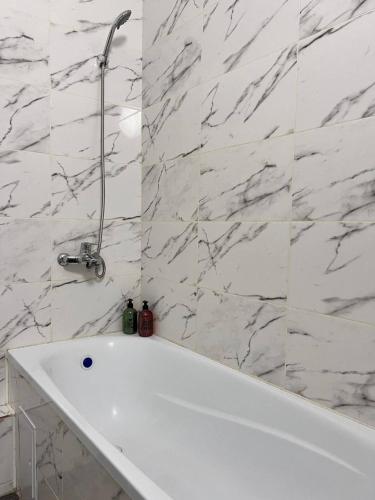 y baño con bañera blanca y paredes de mármol. en Expo New Life 4, en Prigorodnyy