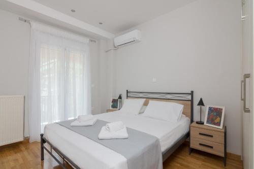 a white bedroom with a bed with two towels on it at One Bedroom Apt w/ Balcony in Athens