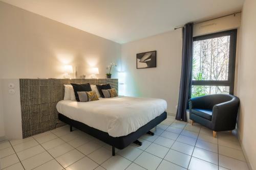a bedroom with a bed and a chair and a window at Garlande Hôtel Avignon Centre in Avignon
