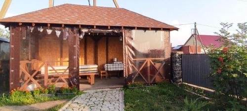 einem hölzernen Pavillon mit einer Bank im Hof in der Unterkunft Гостевой дом Jasmine in Borovoye